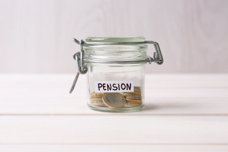 Glass jar with word Pension and coins on white wooden table, closeupの写真素材