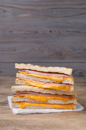 Delicious grilled sandwiches with ham and cheese on wooden table. Space for textの写真素材