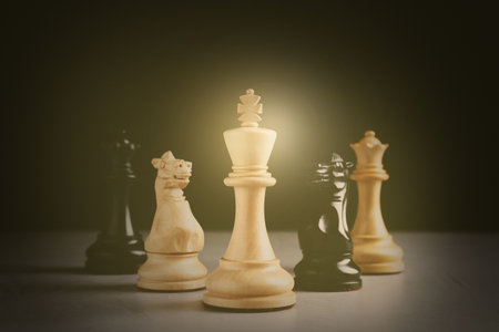 Different chess pieces on gray table against dark background