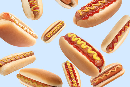 Many tasty hot dogs falling on light backgroundの写真素材