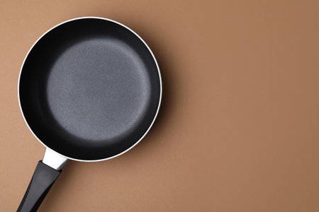 One frying pan on light brown background, top view. Space for textの写真素材