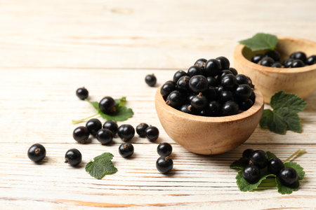 Ripe blackcurrants and leaves on light wooden table. Space for textの写真素材