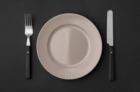 Clean plate with cutlery on black background, flat layの写真素材