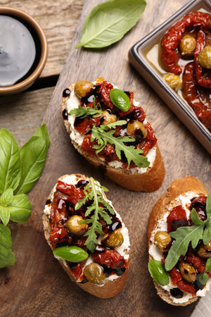 Delicious bruschettas with balsamic vinegar and toppings served on wooden table, flat layの写真素材
