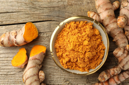 Aromatic turmeric powder and raw roots on wooden table, flat layの写真素材