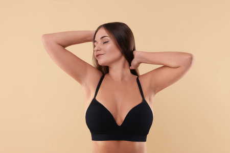 Portrait of young woman with beautiful breasts on beige backgroundの写真素材