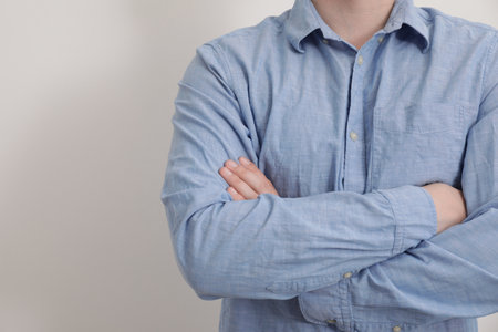 Man wearing rumpled light blue shirt on white background, closeupの写真素材