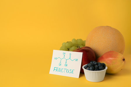 Card with word Fructose, delicious ripe fruits and blueberries on yellow background, space for textの写真素材
