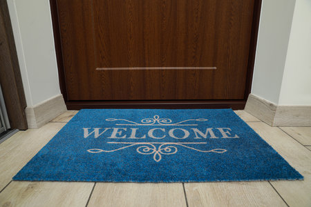 Beautiful blue doormat with the word Welcome on floor near entranceの写真素材