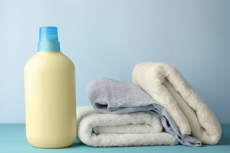 Bottle of fabric softener and towels on light blue tableの写真素材