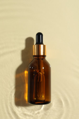 Bottle of cosmetic oil in water on beige background, top viewの写真素材