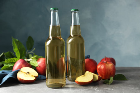 Delicious cider and apples with green leaves on gray tableの写真素材