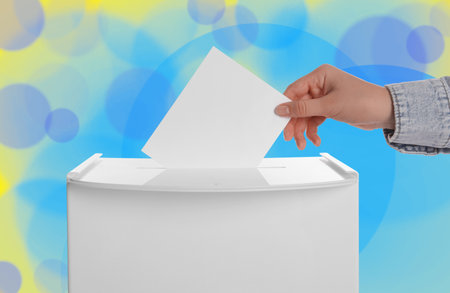 Woman putting her vote into ballot box on color background, closeupの写真素材