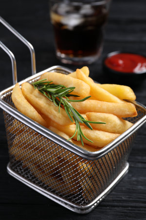 Frying basket with tasty French fries and rosemary on dark wooden table, closeupの写真素材