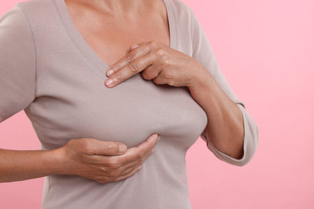 Woman doing breast self-examination on pink background, closeupの写真素材