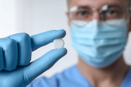 Doctor holding pill on light background, selective focus. Space for textの写真素材