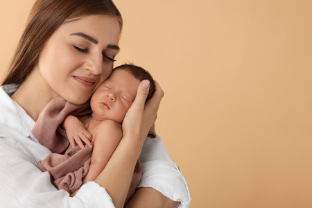 Mother with her cute newborn baby on beige background. Space for textの写真素材