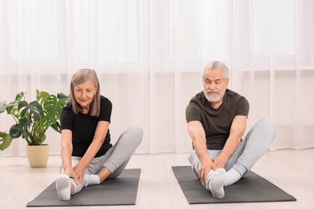 Senior couple practicing yoga on mats at home