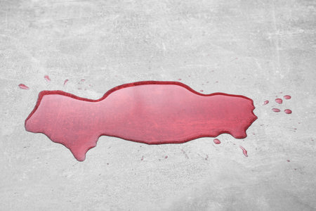 Puddle of red liquid on light gray surface