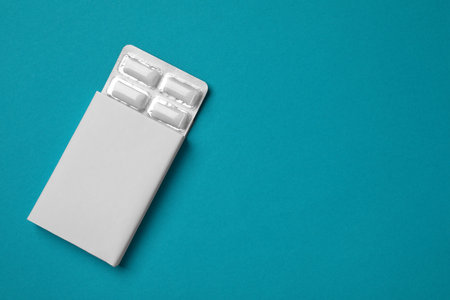 Pack with tasty chewing gums on turquoise background, top view. Space for textの写真素材