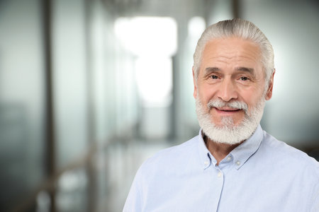 Portrait of handsome senior man in office, space for text