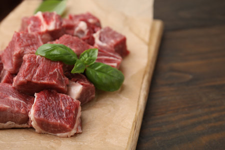 Cut fresh beef meat with basil leaves on wooden table, closeup and space for textの写真素材
