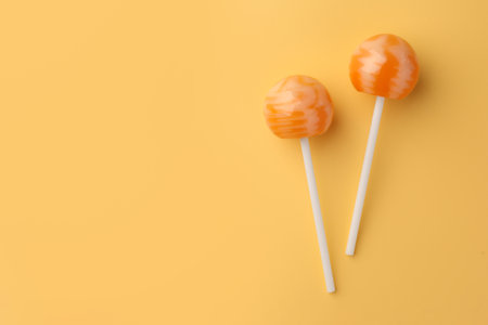 Tasty lollipops on orange background, flat lay. Space for textの写真素材