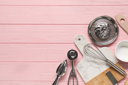 Set of different kitchen utensils on pink wooden table, flat lay. Space for text