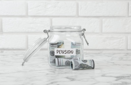 Glass jar with word Pension and banknotes on white marble tableの写真素材