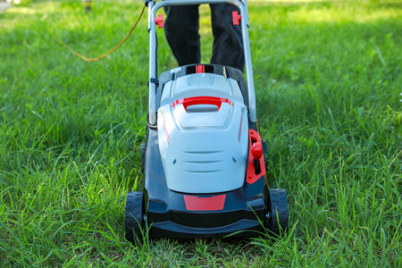 Man cutting grass with lawn mower in garden, closeup