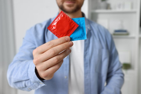 Closeup of man showing packs with condoms indoorsの写真素材