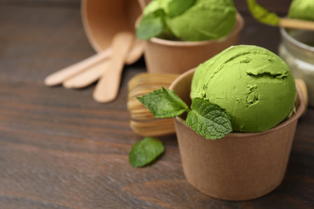 Paper cups with tasty matcha ice cream on wooden table, closeup. Space for textの写真素材
