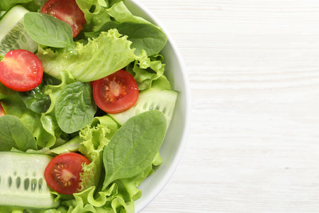 Delicious vegetable salad on white wooden table, top view. Space for textの写真素材