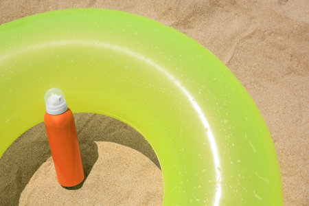 Sunscreen and inflatable ring on sand, above view. Sun protection careの写真素材