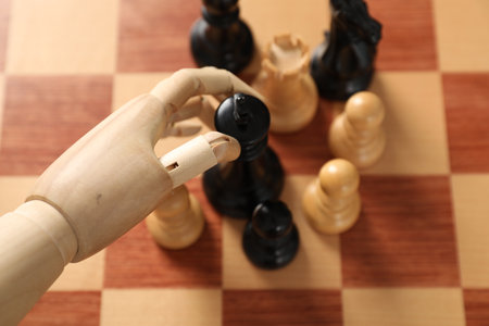 Robot moving chess piece on board, above view. Wooden hand representing artificial intelligenceの写真素材
