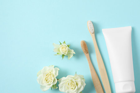 Flat lay composition with toothbrushes, toothpaste and flowers on turquoise background. Space for textの写真素材