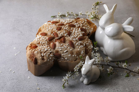 Delicious Italian Easter dove cake (Colomba di Pasqua), flowers and bunny figures on gray table