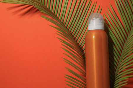 Sunscreen and tropical leaves on coral background, flat lay and space for text. Sun protection careの写真素材