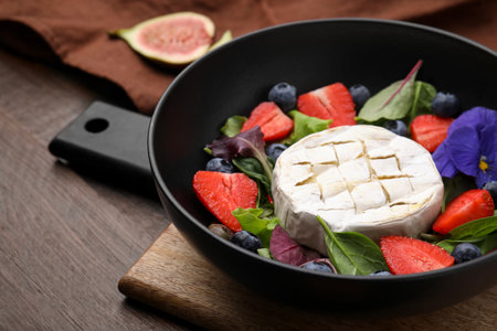 Delicious salad with brie cheese, blueberries and strawberries on wooden table, closeupの写真素材