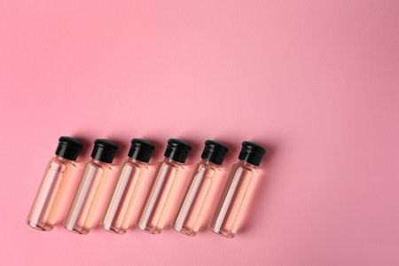 Bottles of cosmetic products on pink background, flat lay. Space for textの写真素材
