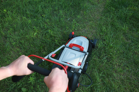 Man cutting grass with lawn mower in garden, above viewの写真素材