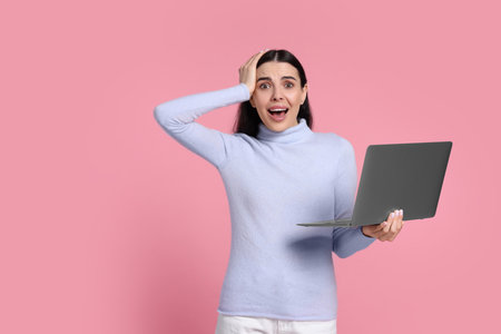 Shocked woman with laptop on pink background, space for text