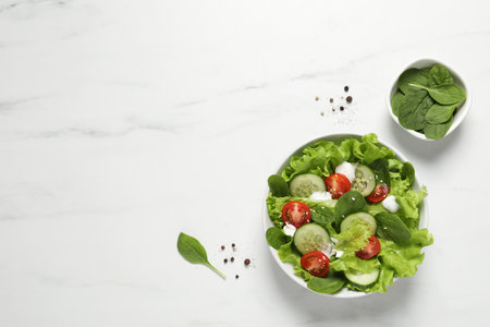 Delicious salad in bowl on white marble table, flat lay. Space for textの写真素材
