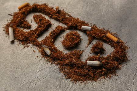 Word Stop made of tobacco and burnt cigarettes on gray textured table, closeup. No smoking concept