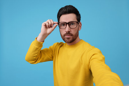 Man taking selfie on light blue background