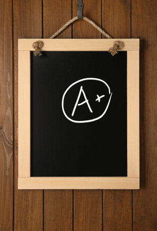 school grade. Small blackboard with chalked letter A and plus symbol on wooden wallの写真素材