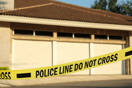 Yellow crime scene tape blocking way to garage outdoorsの写真素材