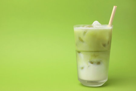 Glass of tasty iced matcha latte on light green background. Space for textの写真素材