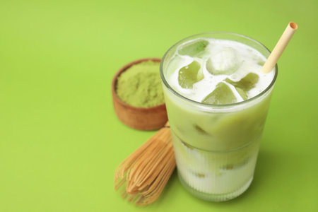 Glass of tasty iced matcha latte, bamboo whiskey and powder on light green background, closeup. Space for textの写真素材
