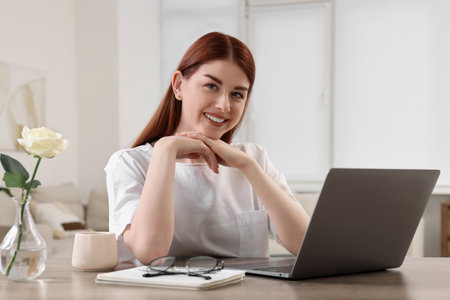 Beautiful woman with laptop at wooden table in room